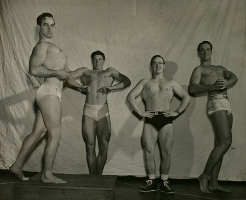 Clarence Harrison doing a side chest pose during a posedown with David Robinson, Richard Flanigan, and Ralph Cameron during the 1949 Mr. Louisville competition